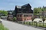 Red museum building with a dark wooden roof, surrounded by a fence