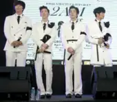 2AM standing onstage in white suits