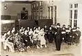 1939年，高雄首創高雄市混聲合唱團，圖為其表演前於高雄女中禮堂內練習的畫面，中間指揮者為女中教師宮崎千藏。