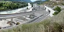 Tunnel entrance, with a river and construction equipment nearby