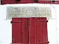 Structural lintel with a lauburu and founders' names, above traditional Basque houses in Lower Navarre, Spain