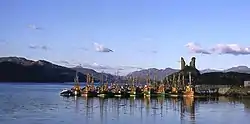 The ruins of an old building sit on top of a prominent hillock that overlooks a pier attended by fishing boats.