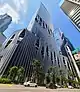 Ground-level view of a 50-storey building, distinct architecture features modern hole designs with trees in them.