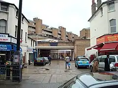 Street with row of shops one of which has a black cat sculpture above its entrance