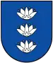 A coat of arms depicting three white flowers lined up vertically with four yellow seeds surrounding each all on a blue background