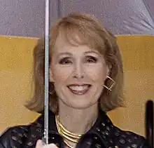 Carroll smiling and holding an umbrella