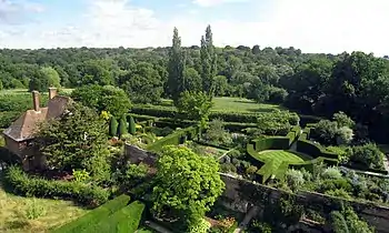 View across garden to fields. Small redbrick cottage to left.