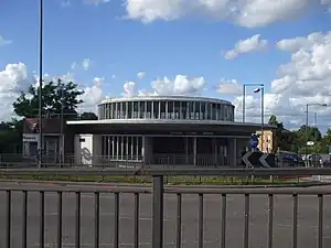 A white building with a rectangular, blue sign reading "HANGER LANE STATION" in white letters all under a blue sky with white clouds