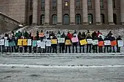 People holding signs on steps of large building