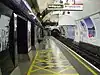 The interior of a building with a rounded ceiling and walls and a white sign hanging from the ceiling reading "Way out Central line"