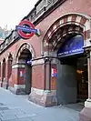 A red-bricked building with a dark blue sign reading "KING'S CROSS ST. PANCRAS" in white letters and several entranceways all under a grey sky