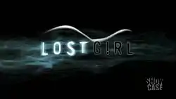 Black background with slender sans-serif words "LOST GIRL" amid curving wisps of white fog resembling long hair and the more solid curve of a female form laying on its side.