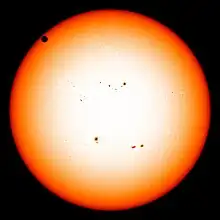 The sun in orange, as seen from the visible spectrum, with Venus in the top left quadrant