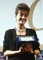 Pascale Ogier at the 1984 Venice International Film Festival, holding an award, looking to the right, wearing a black dress