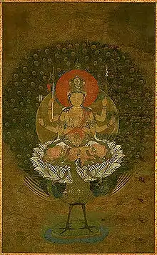 Frontal view of a deity with six arms seated on a peacock.