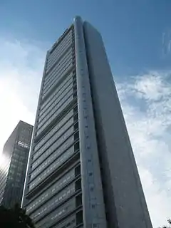 Ground-level view of a 40-storey, box-like building with windowless concrete siding and rounded anterior corners