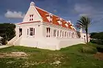 White plantation building with red roof, trees around