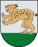 A coat of arms depicting a golden lynx with black spots, a red tongue, white teeth, and white claws standing on its back paws on green turf