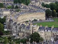 Aerial view of a semicircular terrace of houses with matching fronts but a variety of different styles at the rear