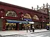 A red-bricked building with a rectangular, dark blue sign reading "RUSSELL SQUARE STATION" in white letters all under a white sky