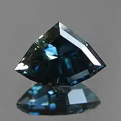 A custom shield cut sapphire from Rock Creek, Montana in deep blue with a slight green undertone or zoning.