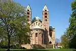 Looking toward the choir of a brick Romanesque cathedral. The twin bell towers, the transept crossing dome, and the roof are green copper.