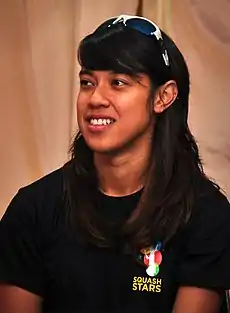 A women in a black t-shirt and a sunglasses on her head smiling.