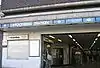 A brown-bricked building with a rectangular, light blue sign reading "STOCKWELL STATION" in white letters all under a light blue sky