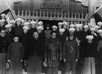 1934年，宋子文、马步芳在青海西宁的清真寺前，与当地男性回族民众合影。回族男性穿着长袍马褂的同时，以佩戴白色缠头的方式，展示穆斯林身份。