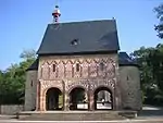 A stand-alone gatehouse surrounded by many trees.