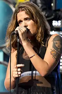 A woman with brown hair holding a microphone.