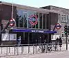 A brown-bricked building with a rectangular, dark blue sign reading "WHITE CITY STATION" in white letters all under a light blue sky